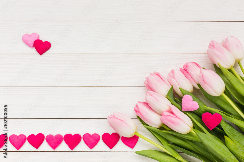 Bouquet of pink tulips on white wooden table decorated with hearts. Top view, copy space. Valentines Day background. Bouquet of pink tulips on white wooden table decorated with hearts. Top view, copy space. Valentines Day background.
