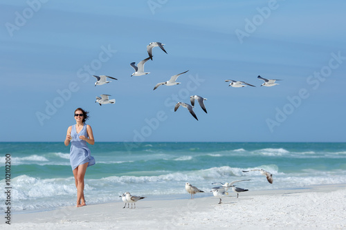 Young woman feeding seagulls on tropical beach, Florida photo