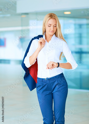 Young businesswoman standing in business center, looking on clock Free Download Young businesswoman standing in business center, looking on clock - GFXLoad