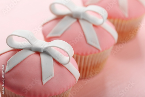 Tasty cupcakes with bow on color wooden background © Africa Studio