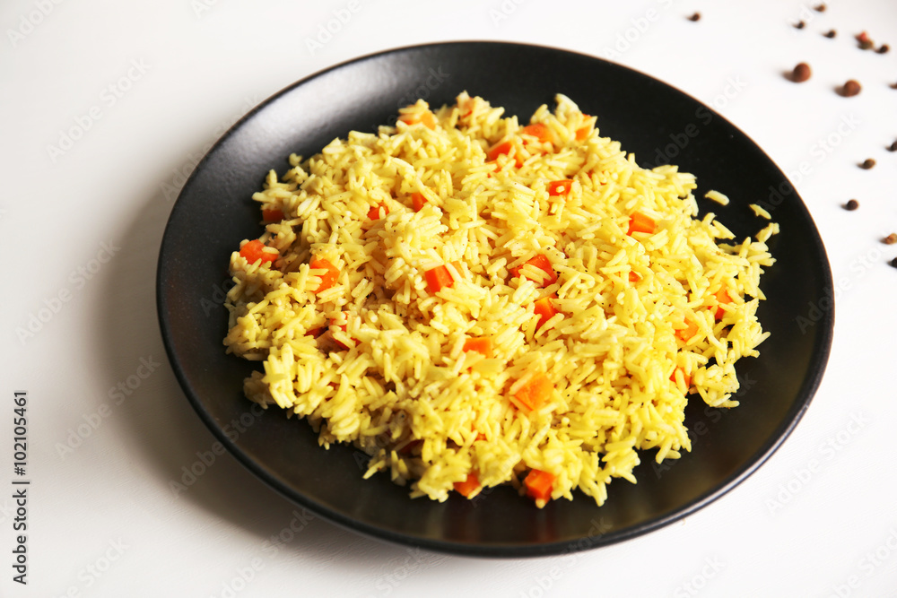 Stewed rice with a carrot on a black plate, close up Stewed rice with a carrot on a black plate, close up