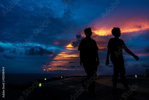 Silhouette of two men on the jack up oil rig helipad with dramatic sun ray in the sky