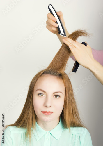 Beautiful young red-haired girl at the hairdresser makes blow drying, shorn bangs, hair polishing