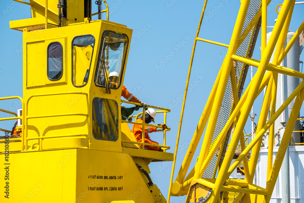 Men working at yellow crane with blue sky Men working at yellow crane with blue sky