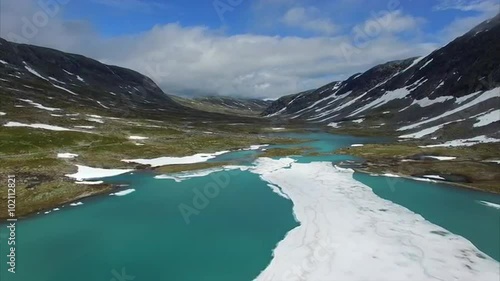 Descending flight above ice on frozen lake next to national tourist route Gamle Strynefjellsvegen in Norway. Aerial 4k Ultra HD. photo