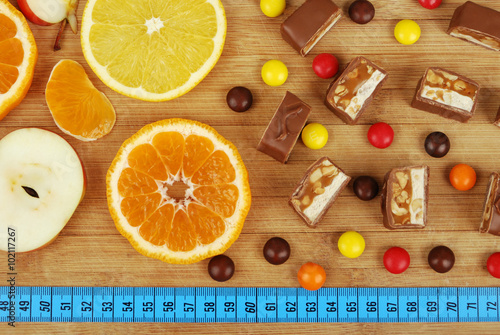 background of sweets, fruit, and a ruler on a wooden board