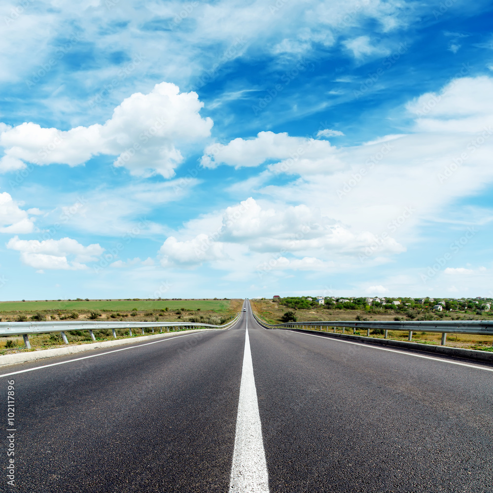 asphalt road with central white line under cloudy sky asphalt road with central white line under cloudy sky