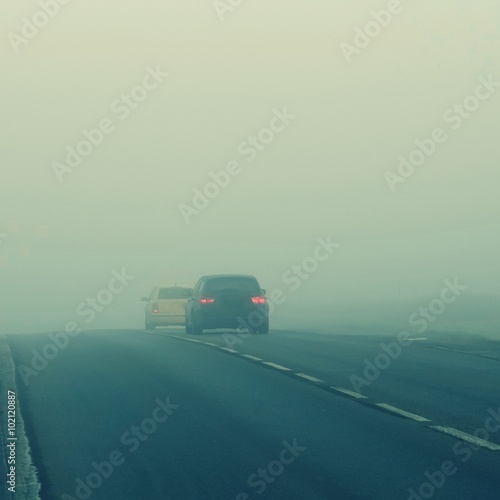 Cars in the fog. Bad winter weather and dangerous automobile traffic on the road. Light vehicles in fog.