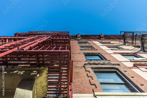 Facade and fire escape of pre-war walkup red brick apartment building in New York City