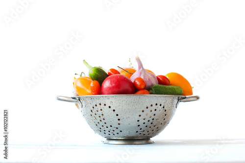 Fototapeta Naklejka Na Ścianę i Meble -  Fresh vegetables in metal colander over white.