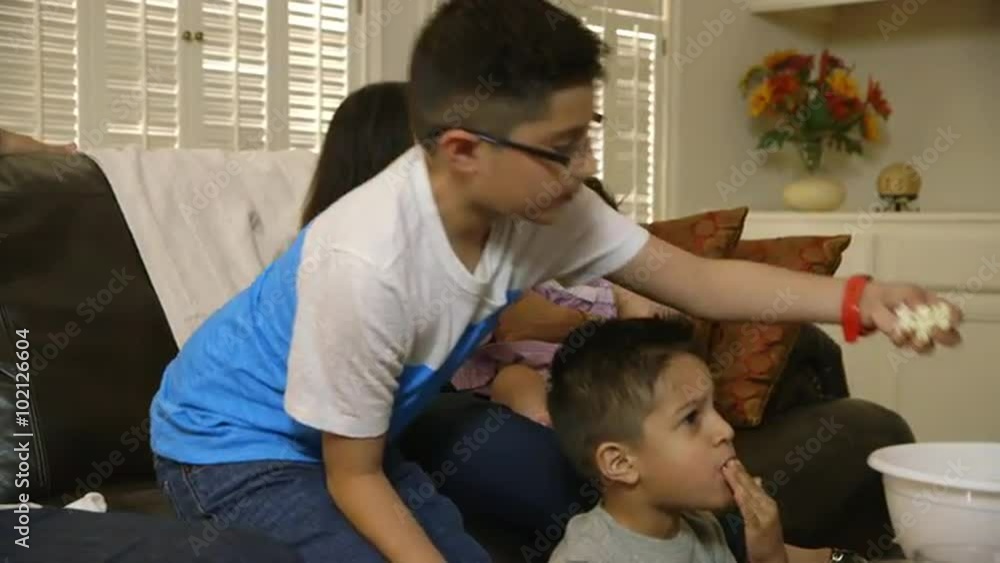 An attractive Hispanic family sitting together enjoying popcorn and television show. An attractive Hispanic family sitting together enjoying popcorn and television show.