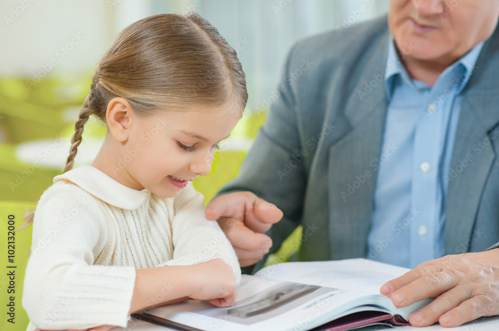 Cute granddaughter attentively exploring a book. Cute granddaughter attentively exploring a book.