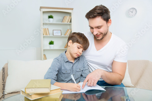 Interested young father is helping son to solve homework © zinkevych