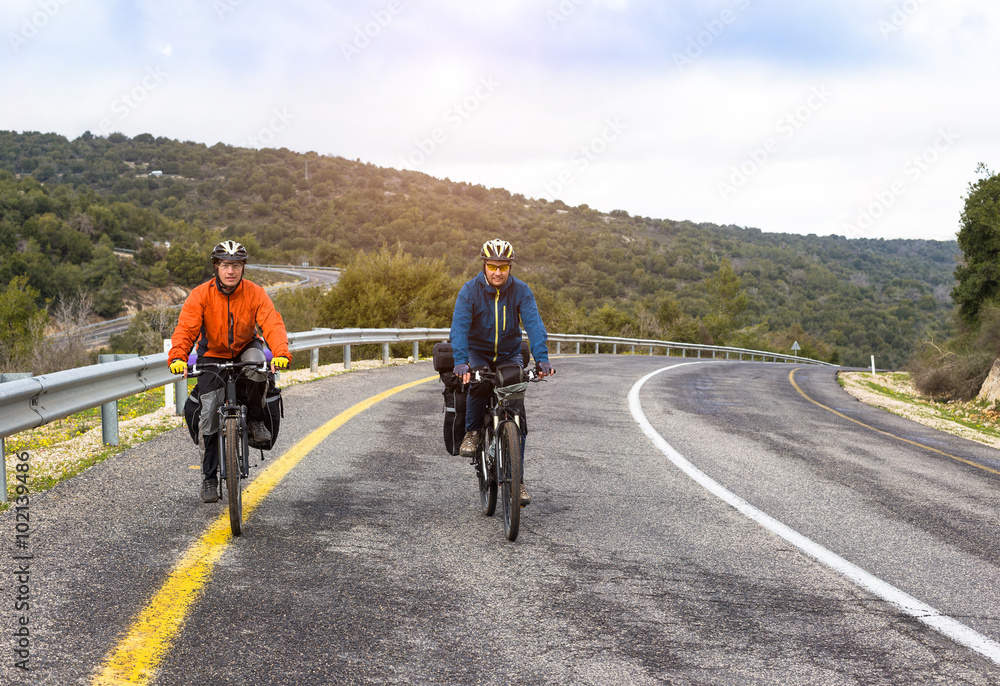Obraz premium Male cyclists riding bike along road. Sunny day