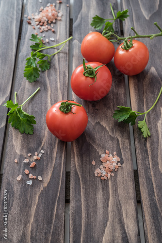 Tomatoes parsley and salt on wooden background