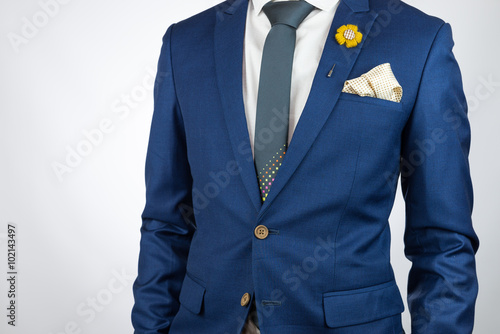 man blue suit necktie, brooch, pocket square