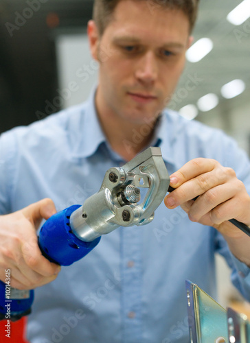 Handsome worker compressing cable connector at the factory.