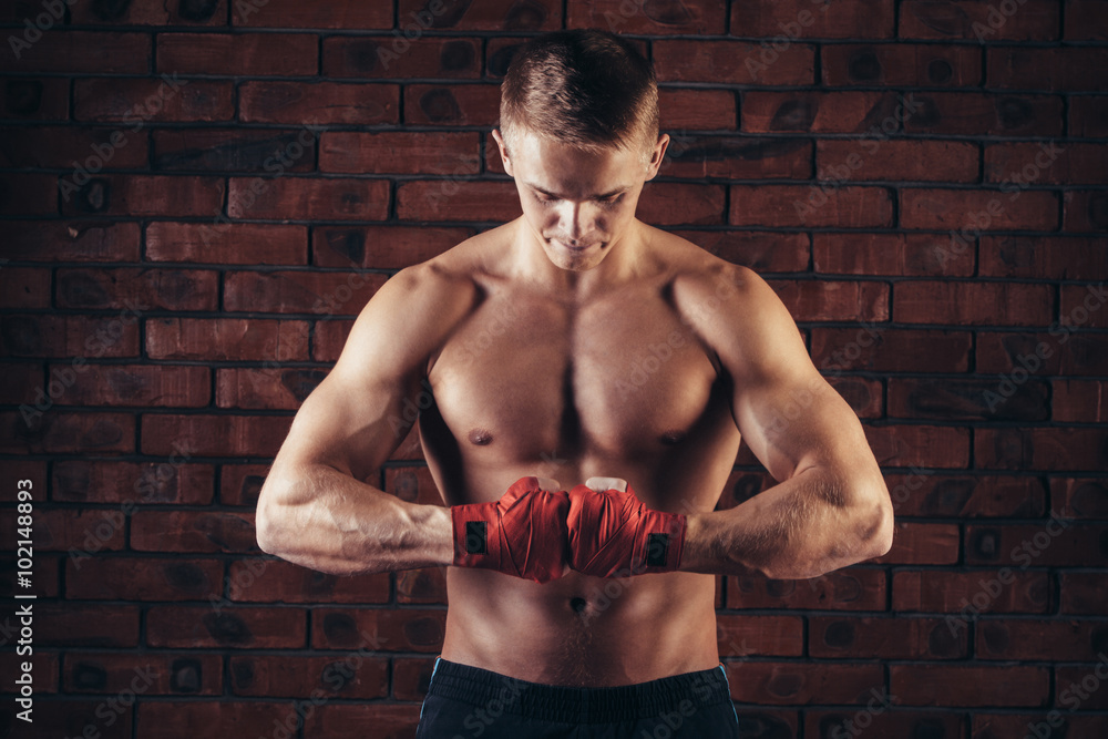 Fototapeta premium Muscular Fighter With Red Bandages against the background of a brick wall