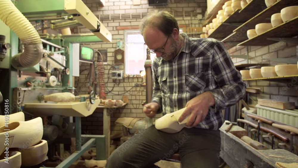 Clog maker is cutting decoration in clog with a gouge Clog maker is cutting decoration in clog with a gouge