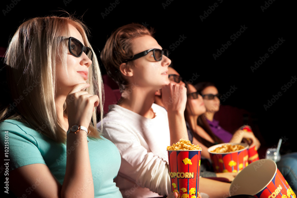 Young couple sitting at the cinema, watching a film