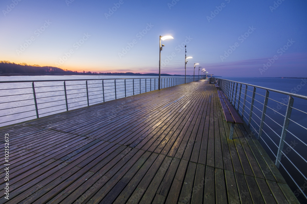 wooden pier by the sea lit by stylish lamps at night