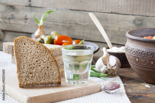 Still life with horilka (vodka) and sliced bread on wooden board photo