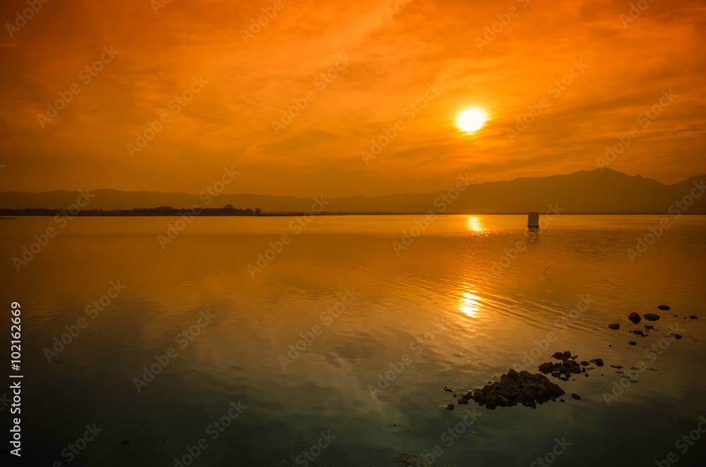 Fototapeta premium Sunset on the lake against the sky in the clouds.