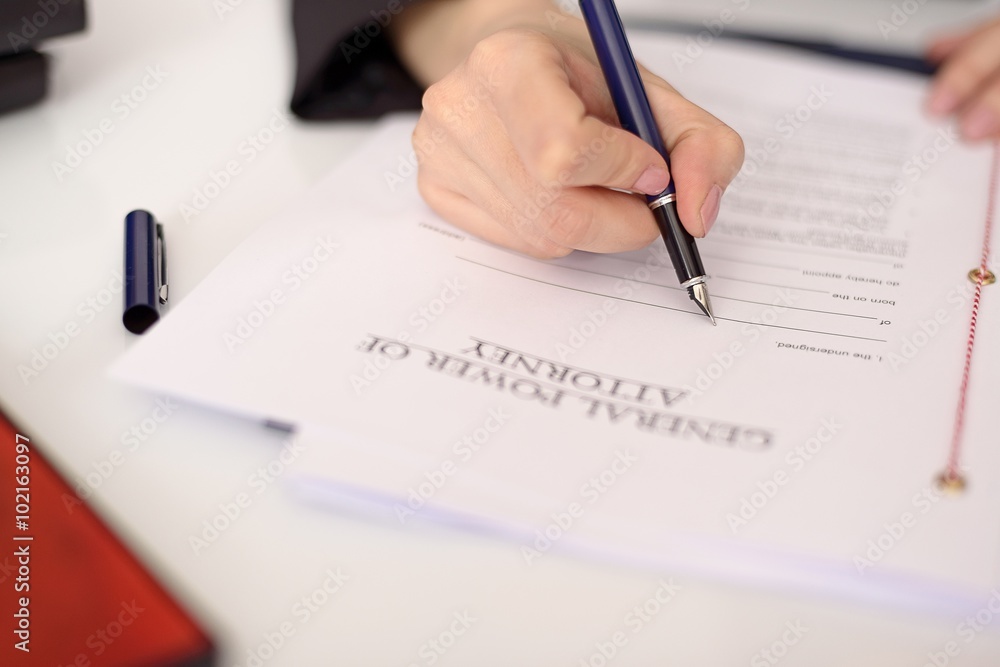 Close-up of a woman's hand filling a power of attorney