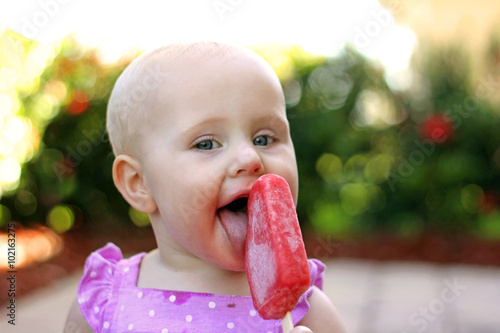 Cute Baby Girl Eating Frozen Fruit Popsicle photo