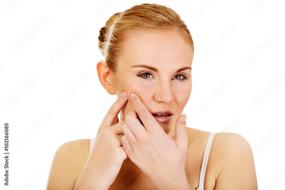Unhappy young woman squeezing pimple on face Unhappy young woman squeezing pimple on face