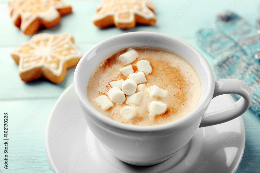 Cup of hot cacao with marshmallow, cookies and warm gloves on blue table Cup of hot cacao with marshmallow, cookies and warm gloves on blue table