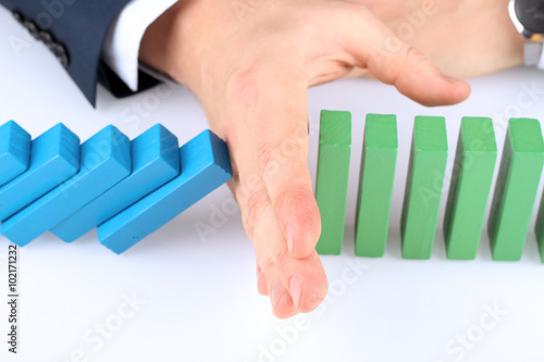 Close-up Of Businessman Stopping The Effect Of Domino With Hand