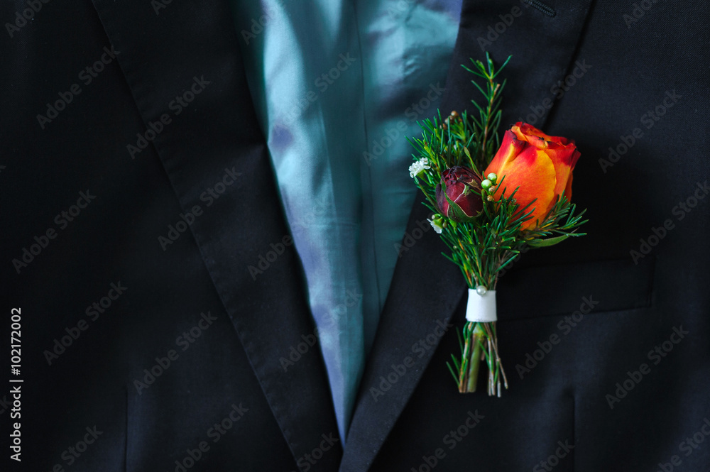 Red rose boutonniere on suit of the groom Red rose boutonniere on suit of the groom