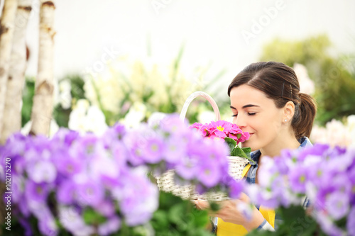 Obraz na plátně springtime woman in flowers garden smell the primroses in wicker wicker basket