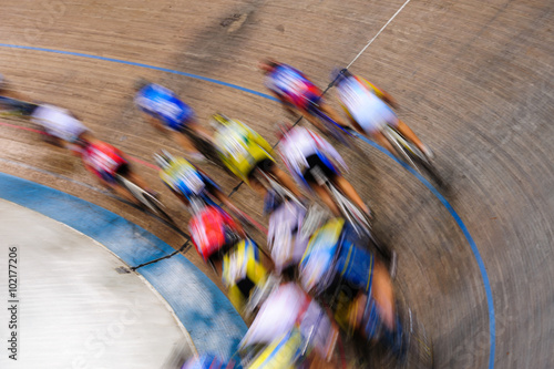 Indiscernible pack of track cyclists racing past on the turn of a velodrome photo