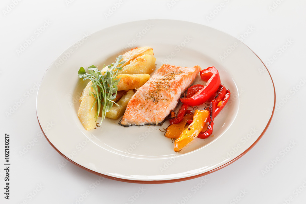 Grilled salmon fillet with vegetables, spices and arugula on a plate Grilled salmon fillet with vegetables, spices and arugula on a plate