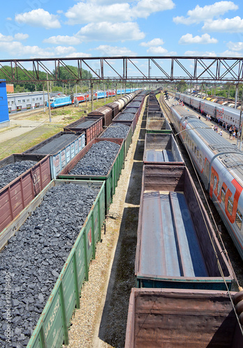 Грузовые железнодорожные вагоны с углем и состав, груженный металлическими деталями, на станции 