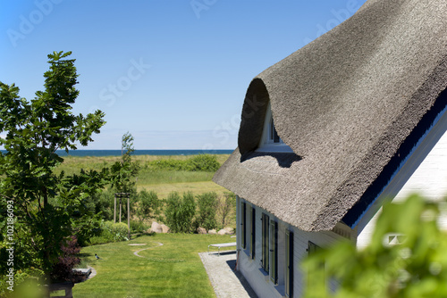 Fotografie, Obraz historical house with thatched roof and blue sky at the German Baltic Sea coast,