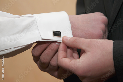 each wears cufflinks on the sleeves of the groom