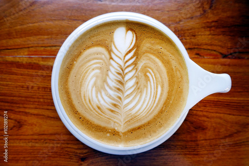 cup of latte art coffee on wooden background