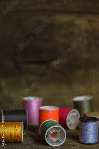 Set of Multi-Colored Sewing Spools on Wood Background