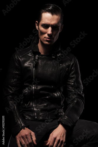 sexy biker in black leather jacket posing seated in dark © Viorel Sima