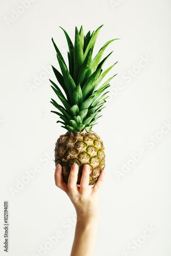 Female hand holding ripe pineapple on a white background