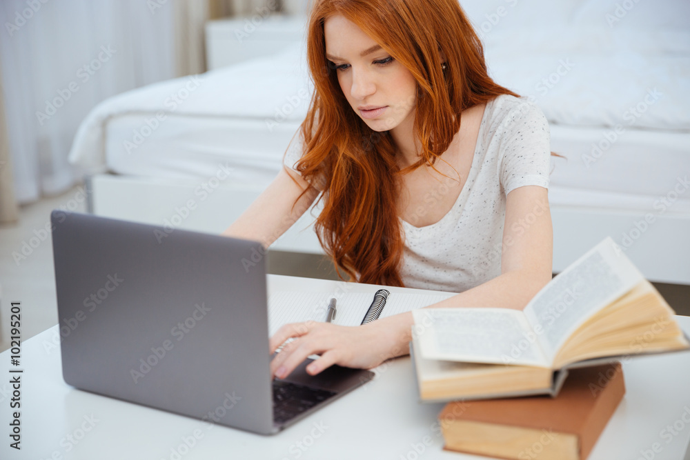 Woman using laptop computer while doing homework Woman using laptop computer while doing homework