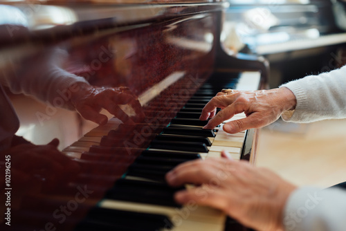 experienced old hands closeup playing piano