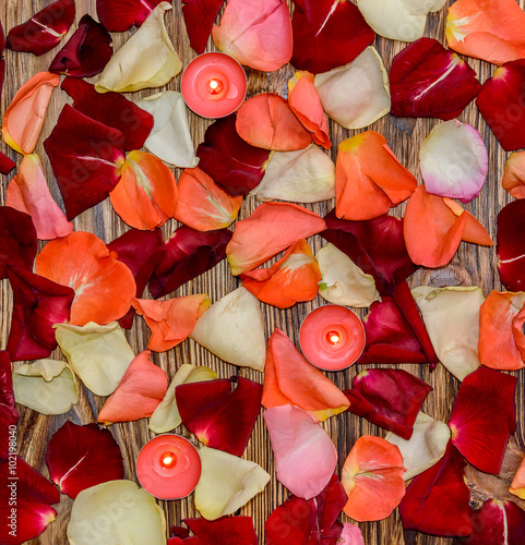 Rose petals with candles on wood background