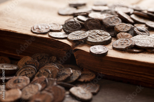 Pile of ancient coins on the very old book