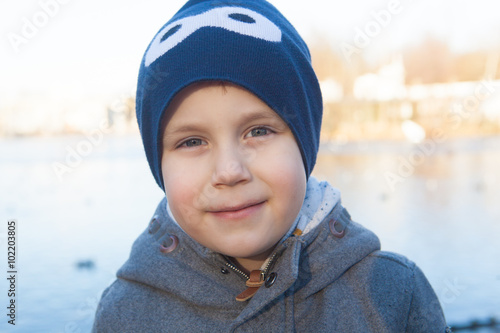 Little boy having fun on the bank of the lake at winter day