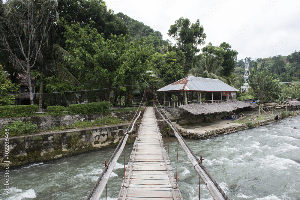 Puente de madera sobre río en un pequeño pueblo  en la jungla de de Sumatra, Indonesia