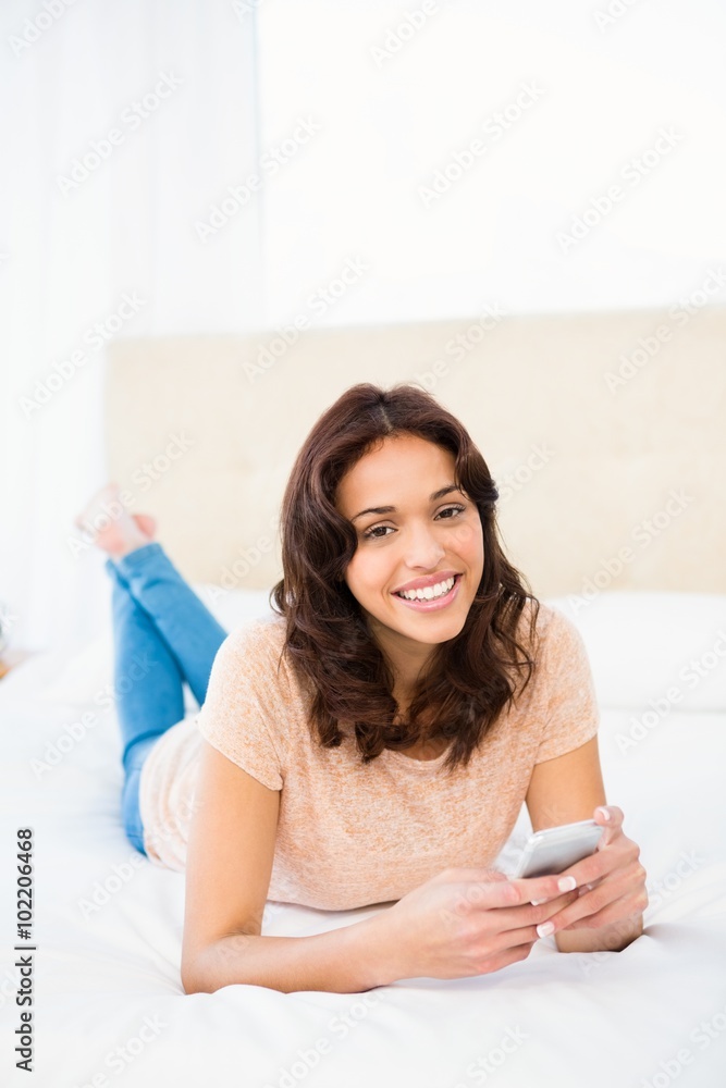 Smiling woman using smartphone while lying on bed Smiling woman using smartphone while lying on bed